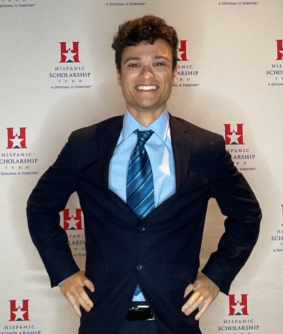 A picture of Marcos Morales in a Navy Blue suit with a blue tie and a blue shirt. The background is white.